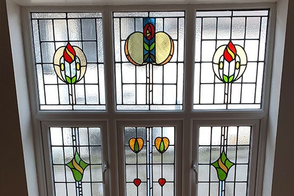 Stained glass window featuring floral and geometric designs in vibrant colours.